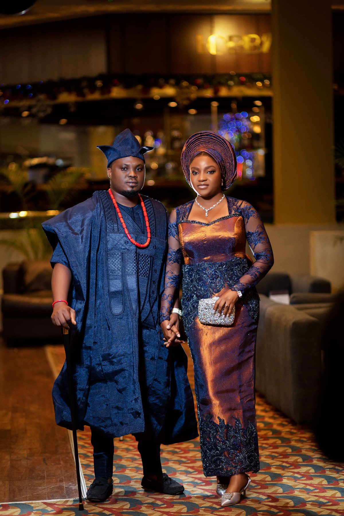 Couple posed together in an elegant reception hall strung with lights