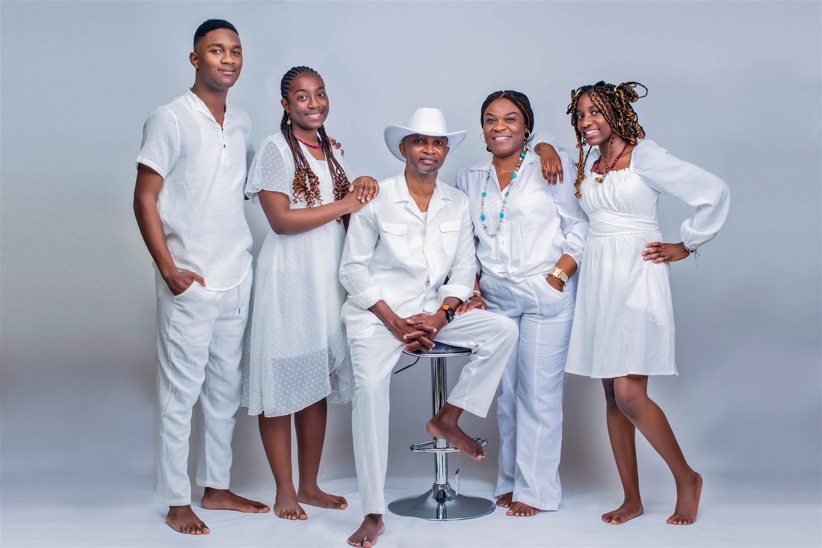 Family of five posed together in coordinated white outfits