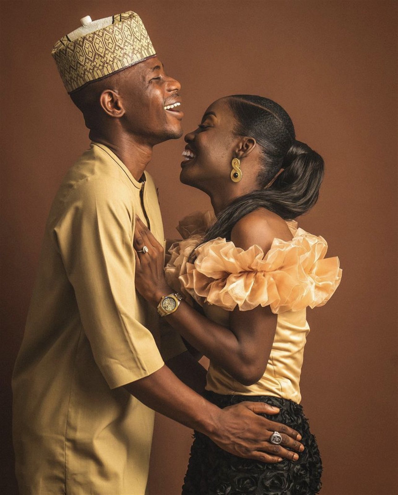Groom and bride laughing together in gold traditional attire