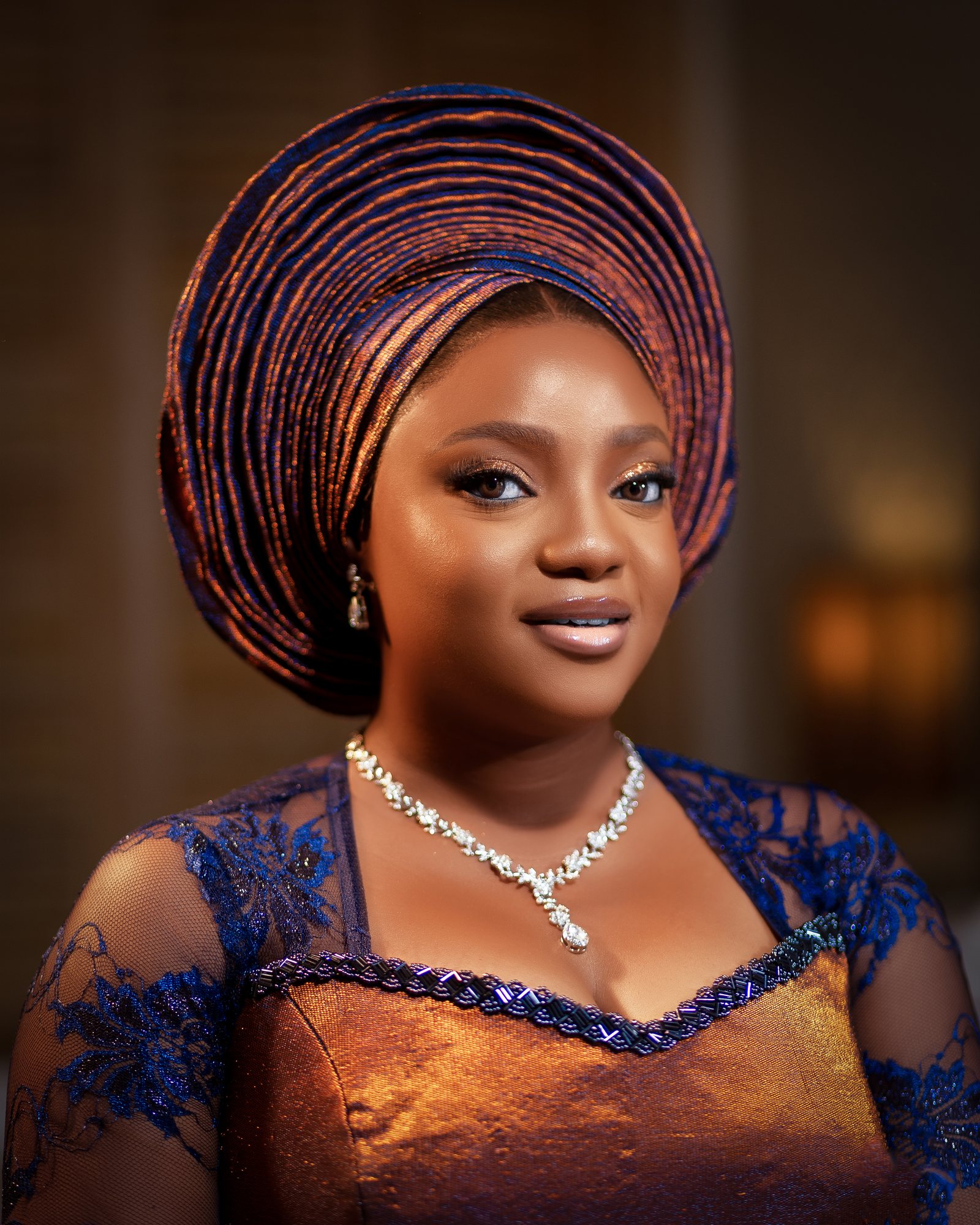 Bride in a beaded gele and fine jewelry in warm evening light